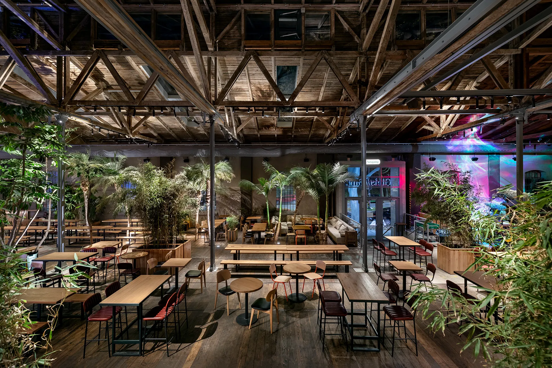 Wide restaurant view with garden structure, layered seating and atmospheric light.